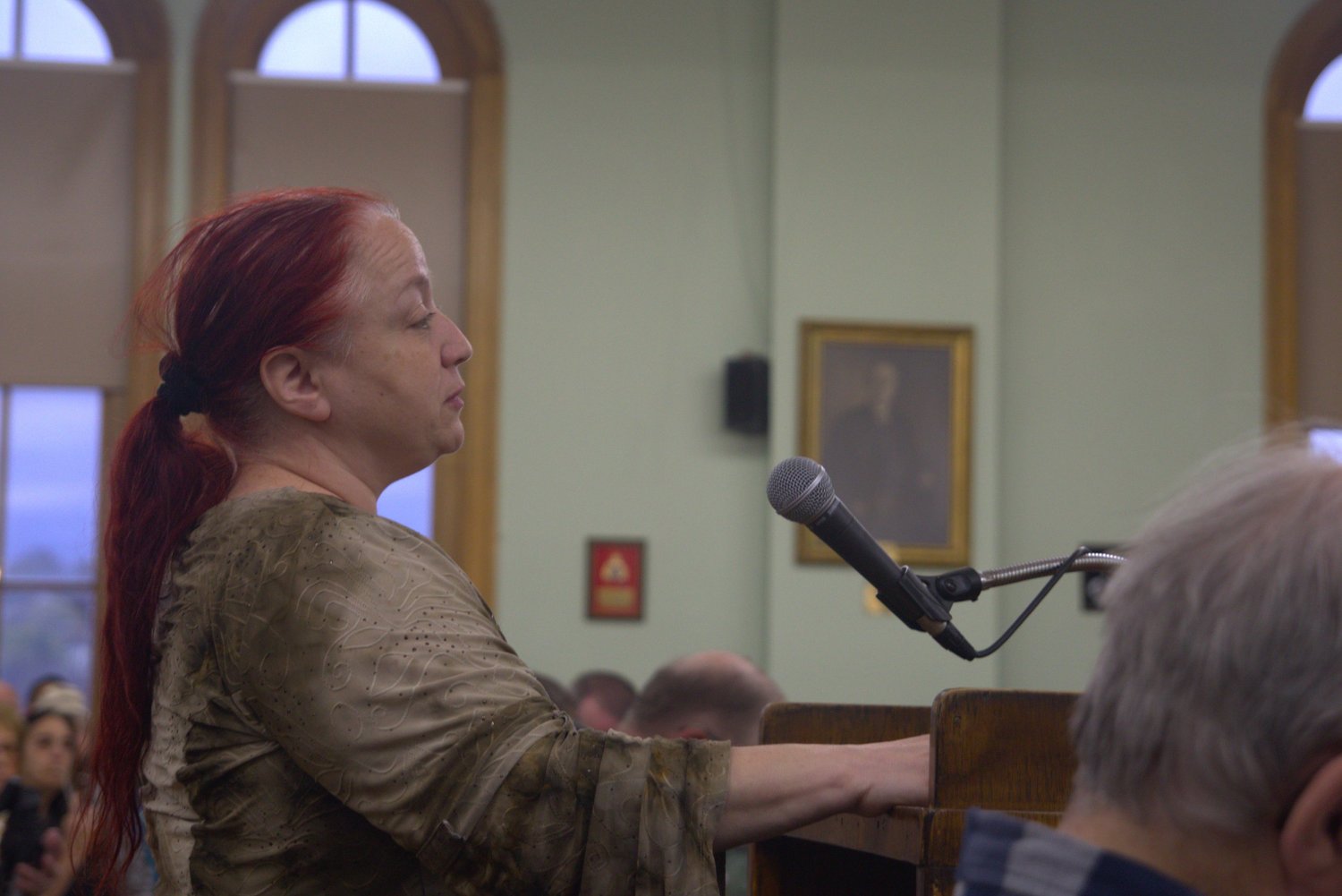 Advocate testifying at a microphone during a State House budget hearing