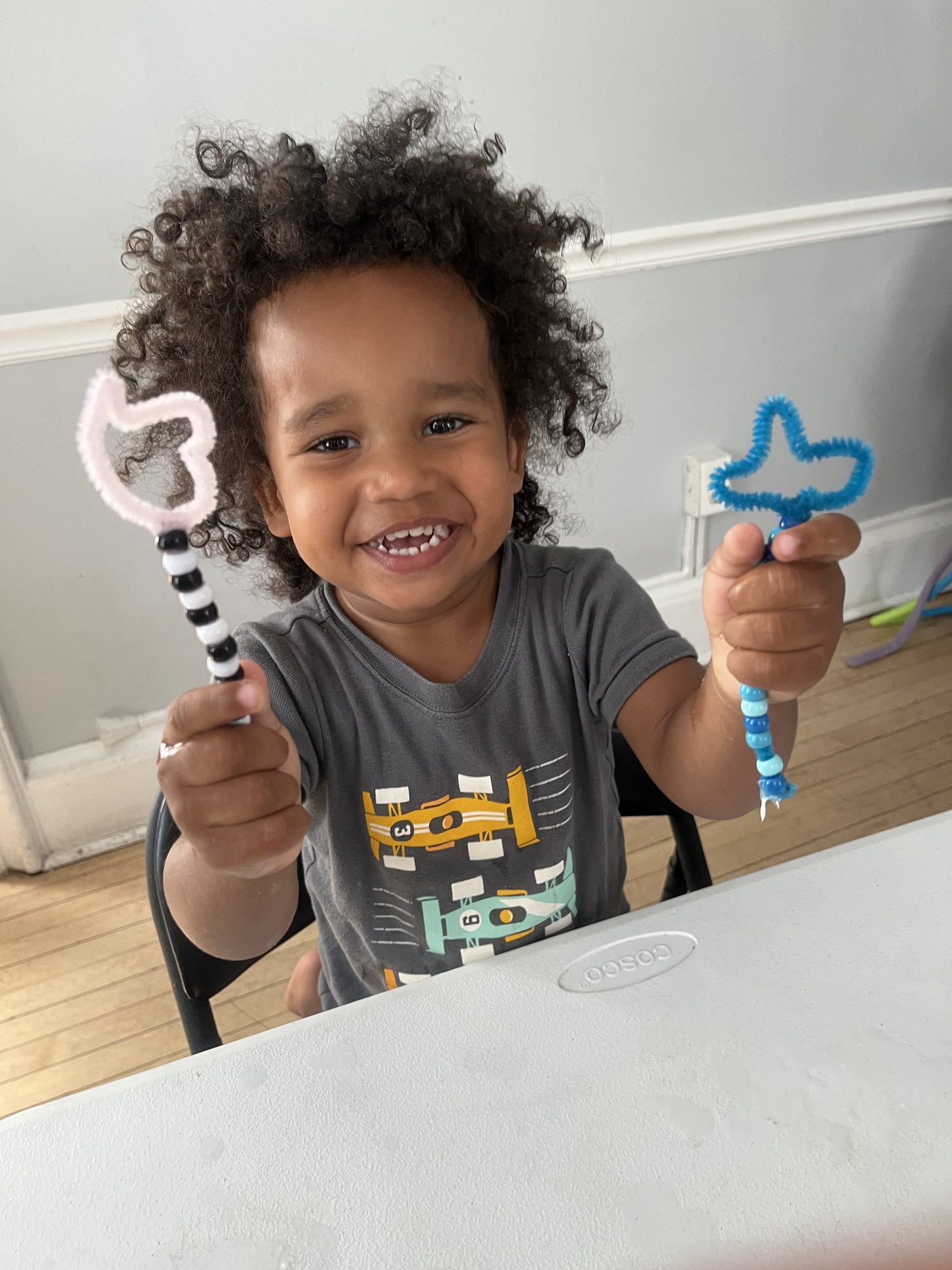 Child holding up pipe cleaner crafts