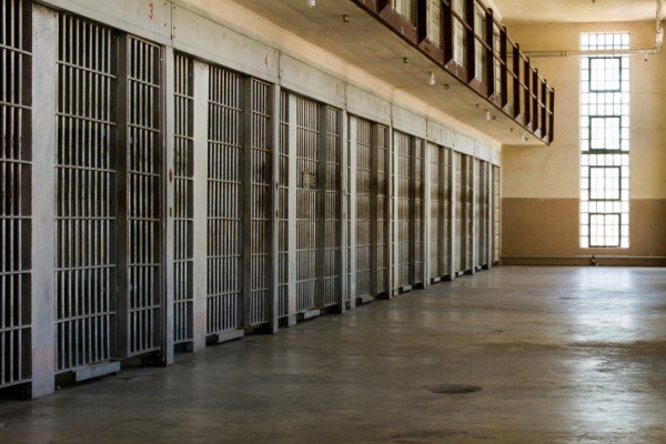 Empty row of prison cells along a cellblock corridor