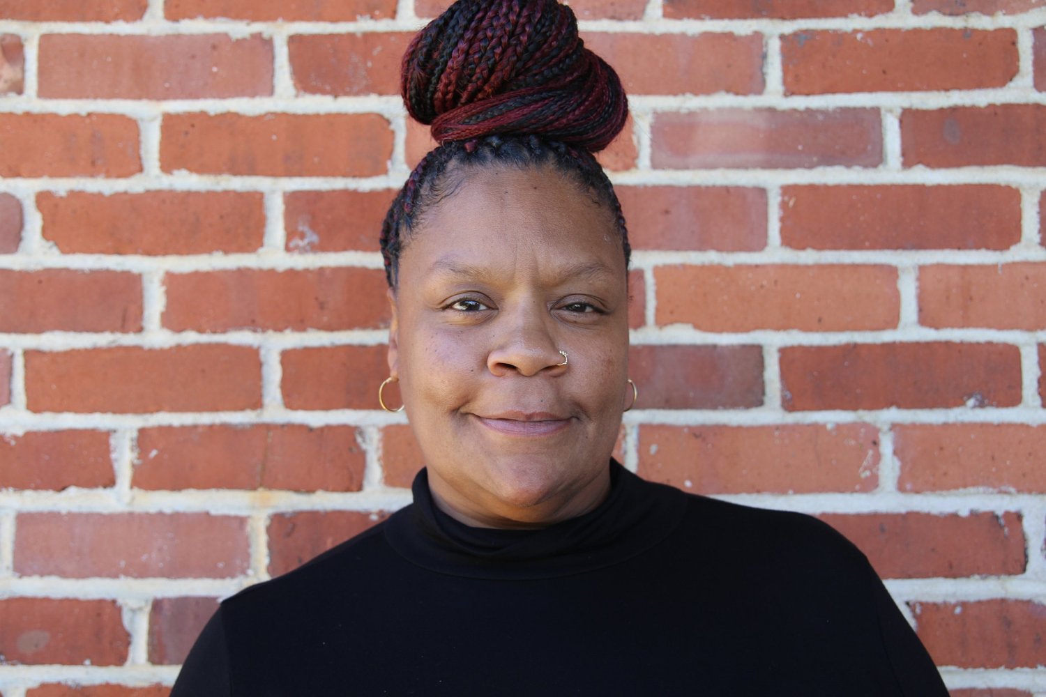 Portrait of Deputy Director Dina Bruce against a brick wall