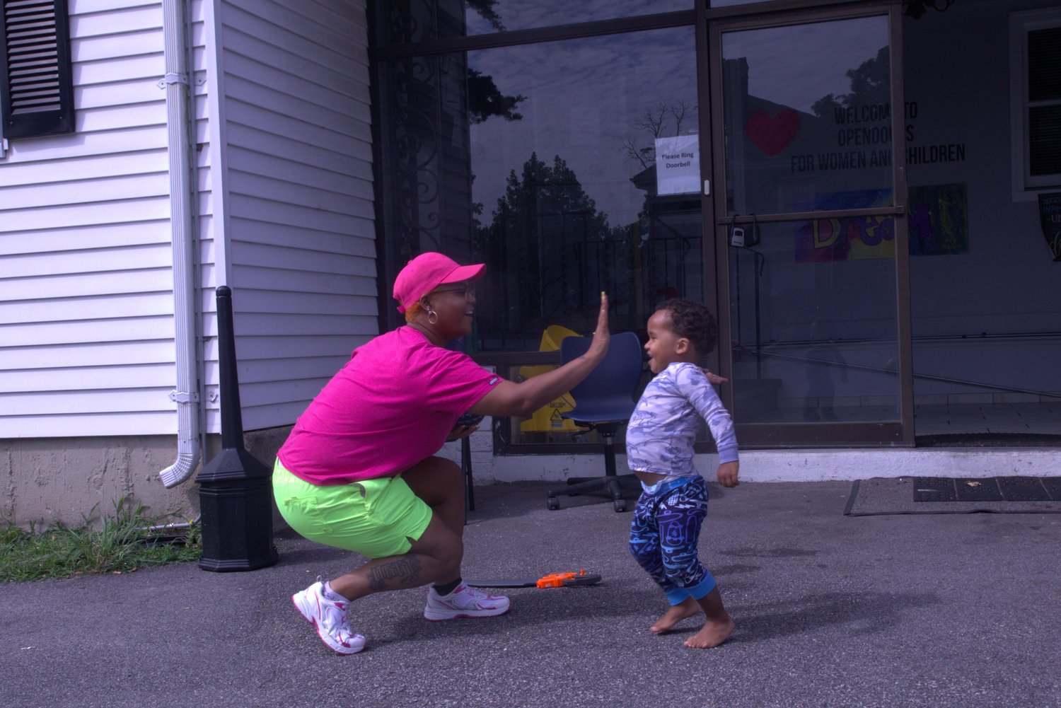 Staff member giving a high five to a toddler outside the She Thrives house
