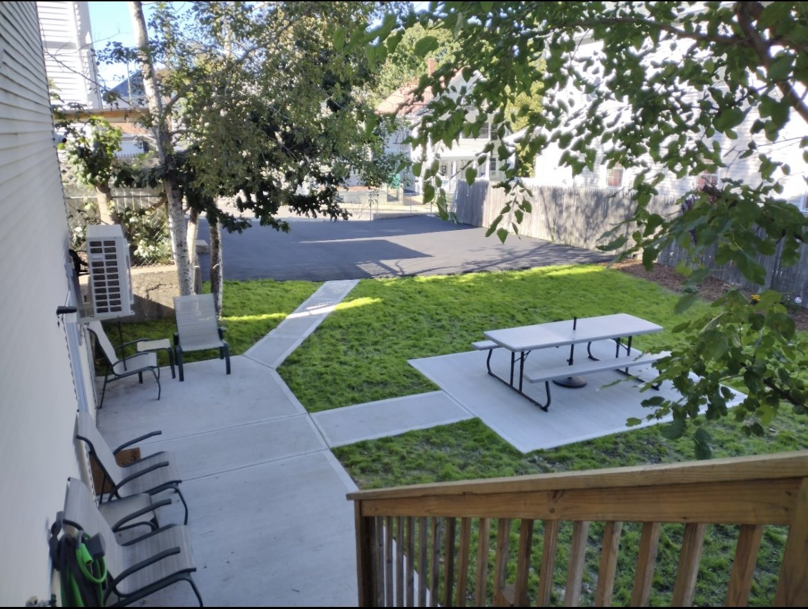 Backyard with lawn, picnic table and patio chairs at the Foundations house