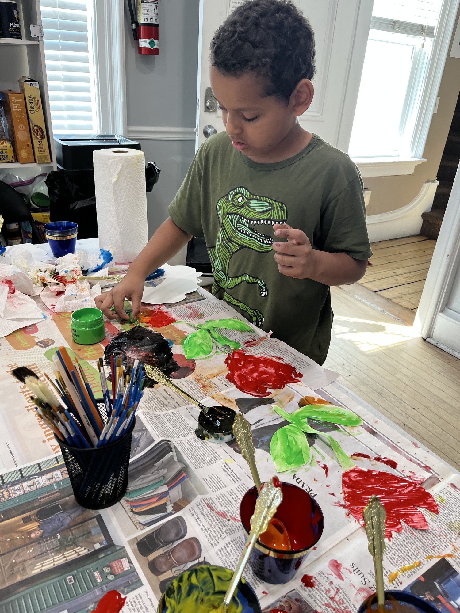 Child painting at a craft table at the She Thrives house