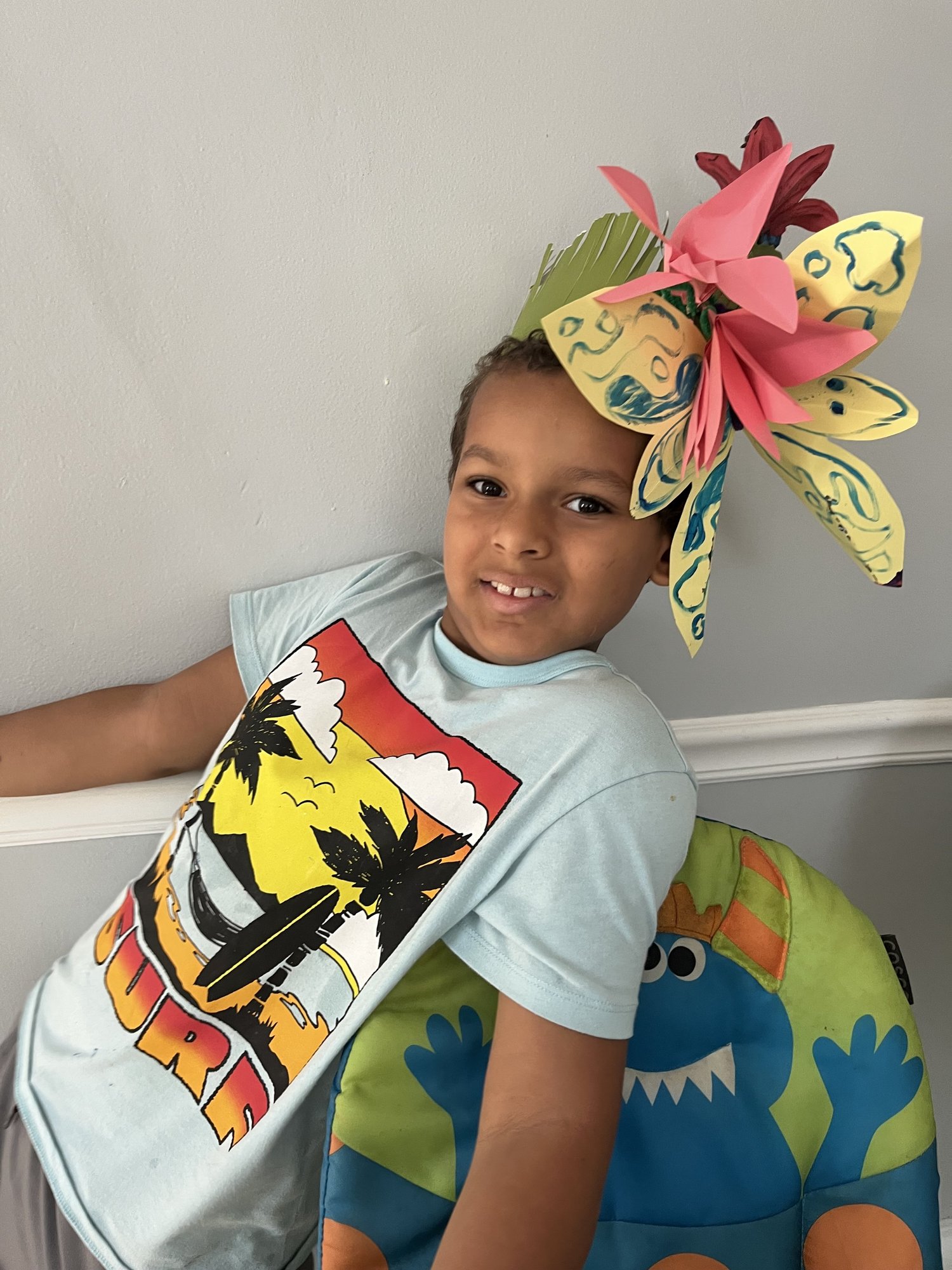 Child wearing a paper flower crown made at the She Thrives house