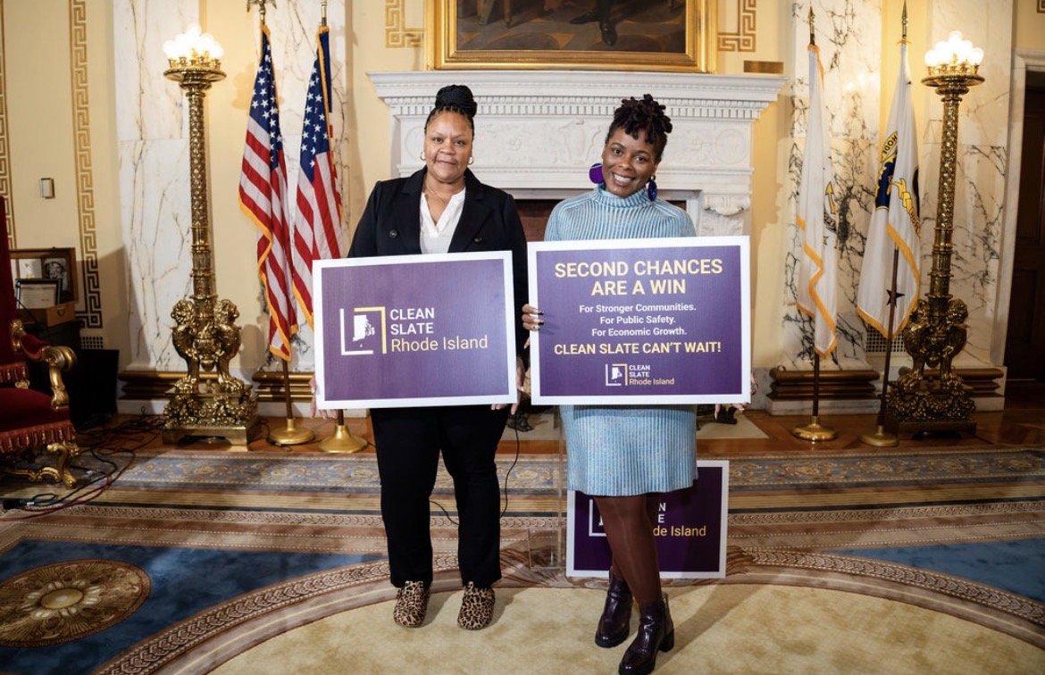 Two advocates at the RI State House holding Clean Slate Rhode Island signs: Second chances are a win