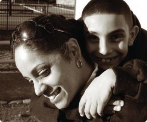 Sepia photo of Koren with a child hugging her from behind