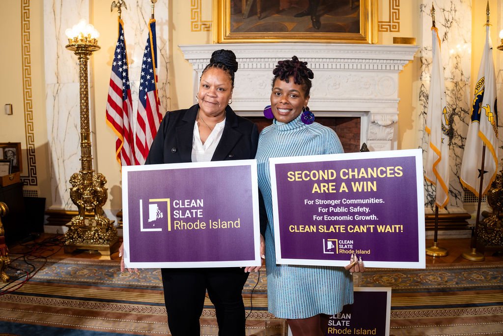 Two advocates at the RI State House holding Clean Slate Rhode Island signs