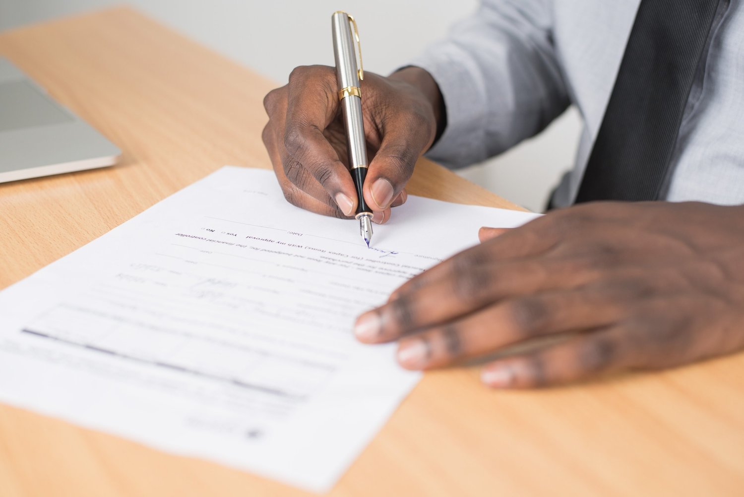 Person signing an application form at a desk