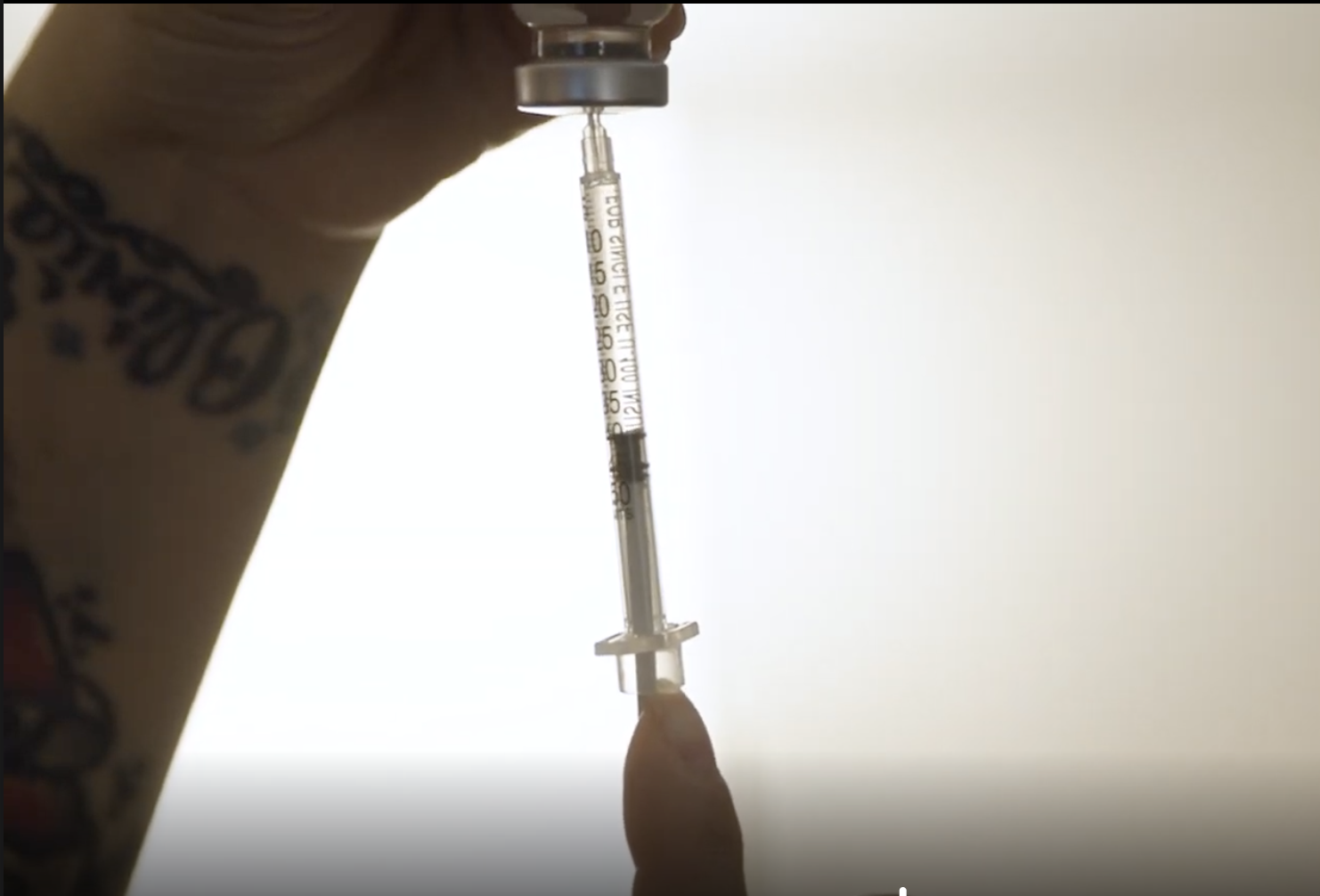 Syringe drawing medication from a vial